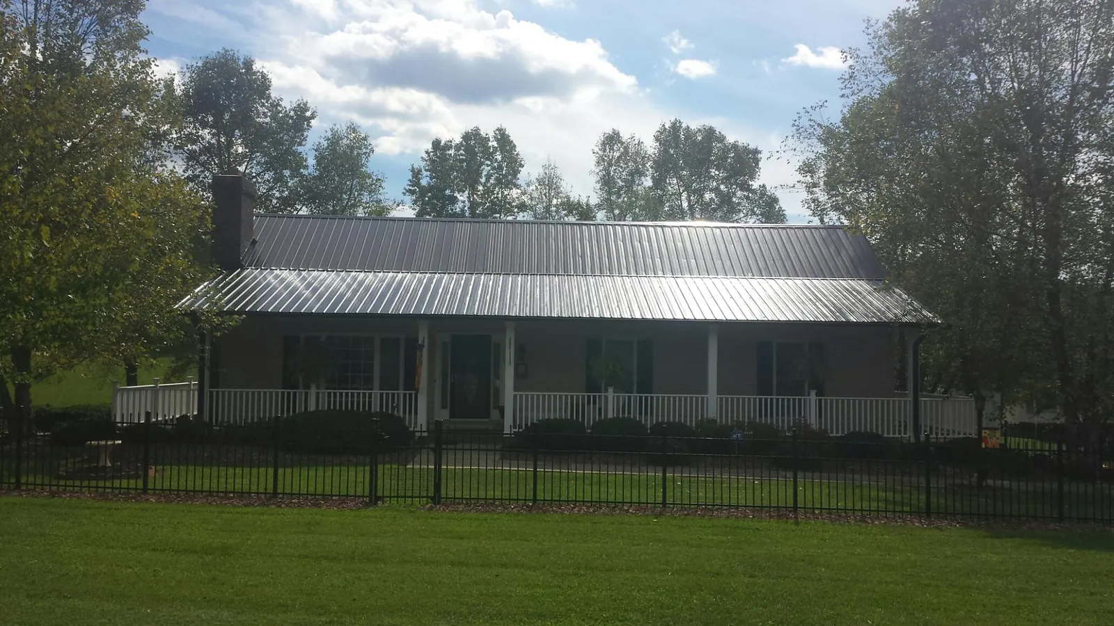 Gray metal roof on a brick ranch with a full width front porch — Gutter Guard Installation work by our crew in Sprague