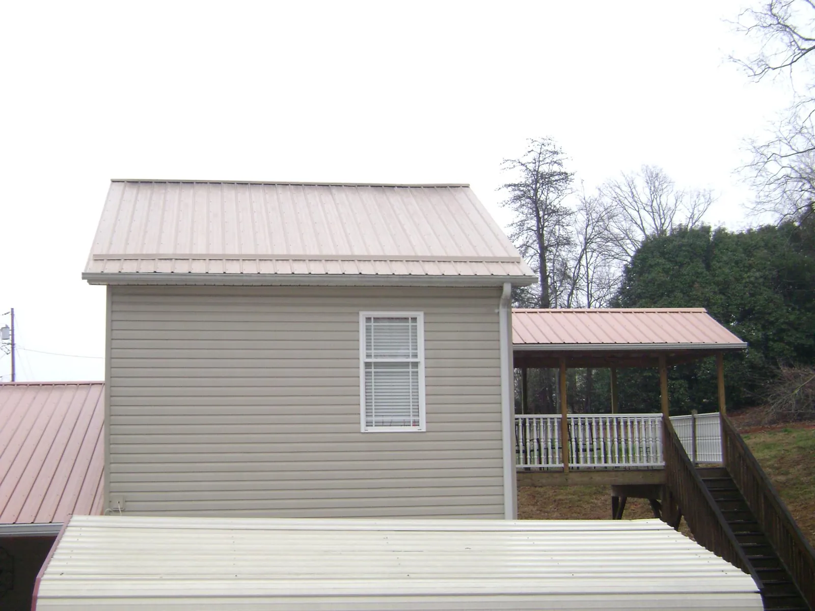 Tan metal roofs on a two story addition and attached porch, from a Roof Replacement job in Sprague